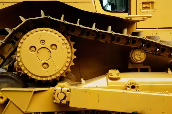 Close up of treads for a bright yellow piece of construction machinery.