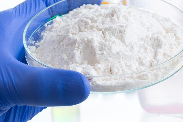 Blue glove holding a petri dish with chemical dust inside portraying dust collection.