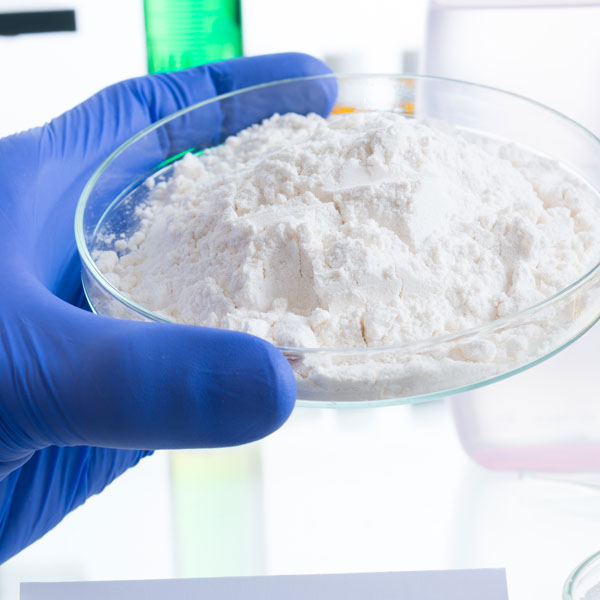 Blue glove holding a petri dish with chemical dust inside portraying dust collection.