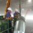 Green crane loading big blue RoboVent containers, preparing to install industrial dust collection system