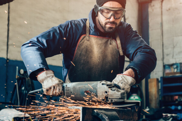 Man grinding metal in an area without dust or debris in the air, because solutions for fabrication dust collection are in use