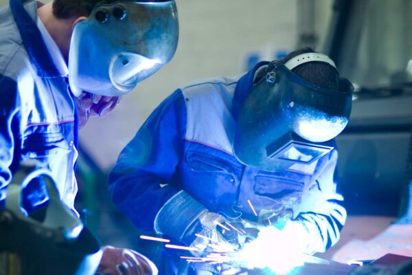 Student and teacher welding with no dust particles, due to fume collection system for welding schools