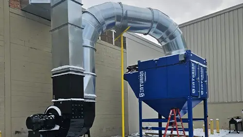 A blue Senturion dust collector from RoboVent installed outside an industrial facility.