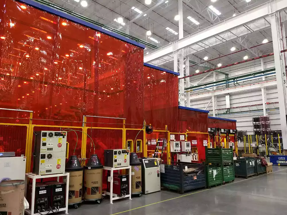 A custom Streamline Hood enclosure from RoboVent, with orange translucent walls and blue framing with equipment in the foreground. The modular hood system shows several enclosures of different sizes and heights.