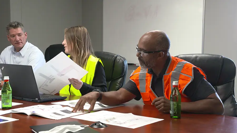 Engineering team Engineering team reviews dust collection system design plans during a project meeting.