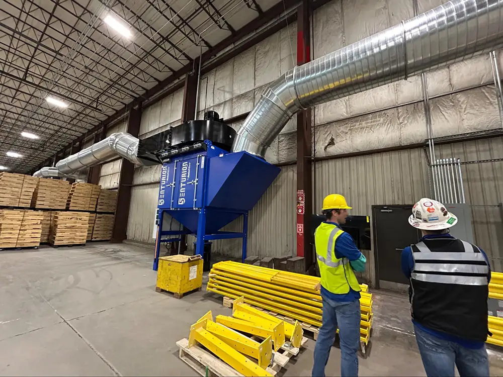 Technicians inspect dust collection equipment and ductwork during an on-site facility testing and evaluation visit.